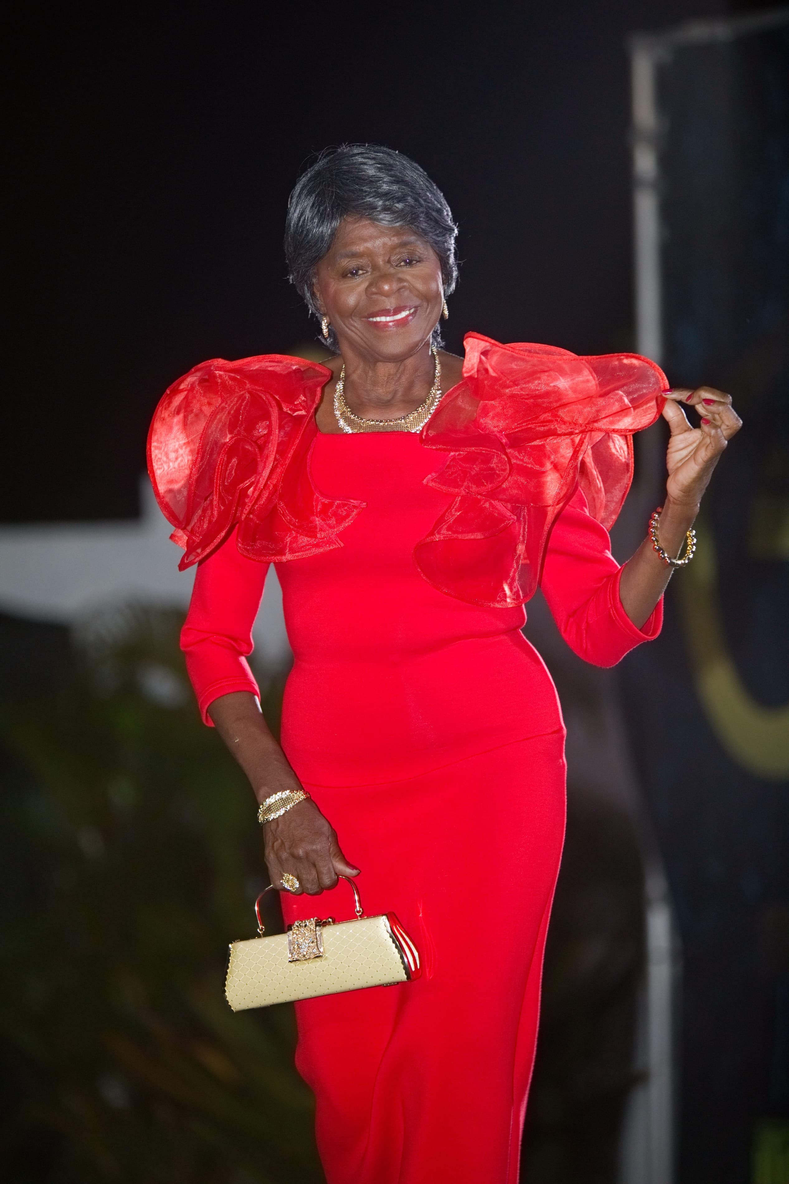 Une participante souriante défile dans une robe rouge.